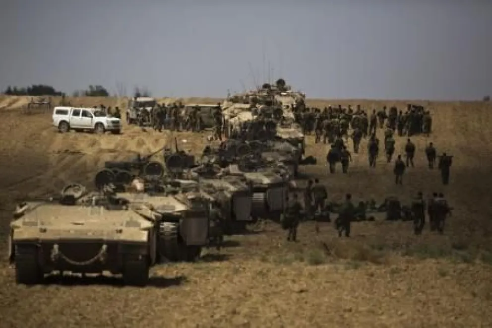 En la imagen, soldados israelíes caminan junto a sus tanques tras regresar a Israel desde la Franja de Gaza.