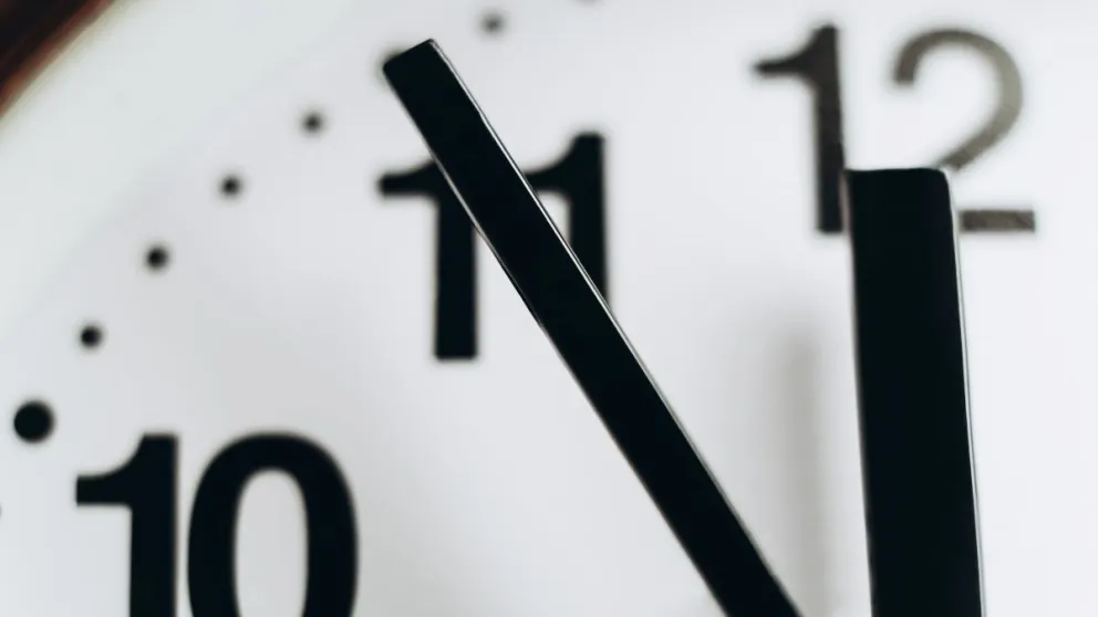 Low angle macro view of round wall clock showing 11:55.